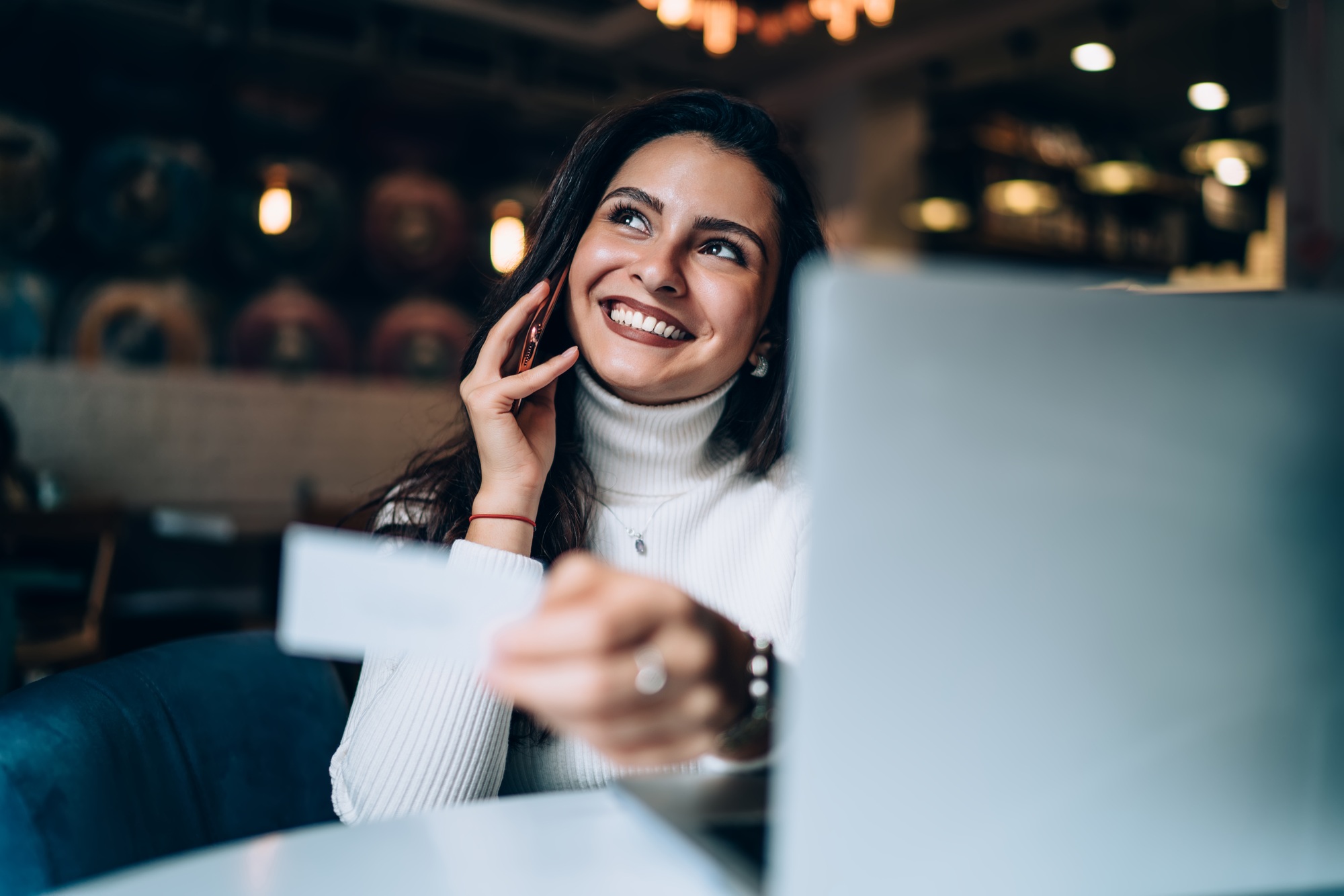 successful woman dialing contact number during cellular phoning at table with laptop